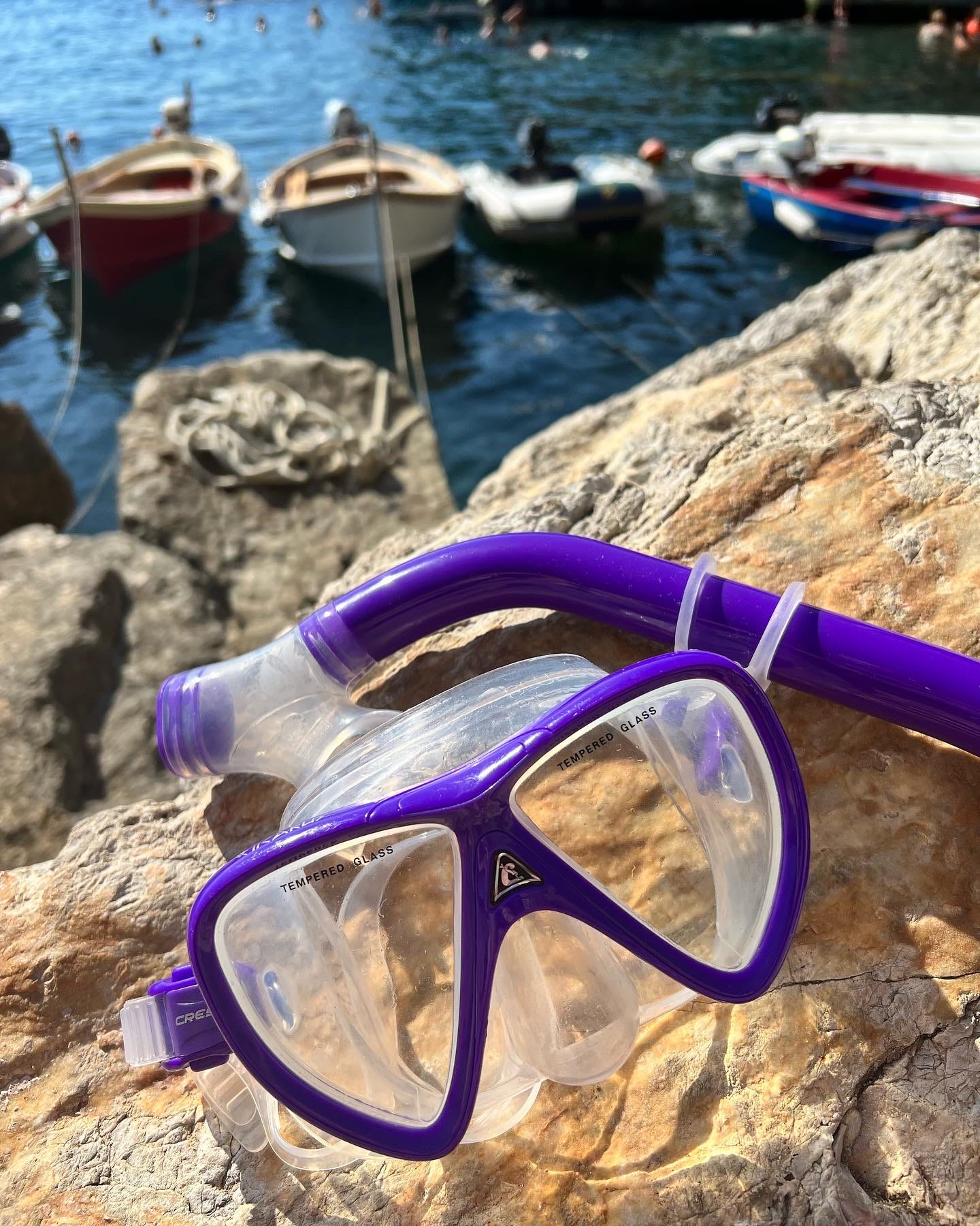 Snorkeling mask on rocks with boats in the background