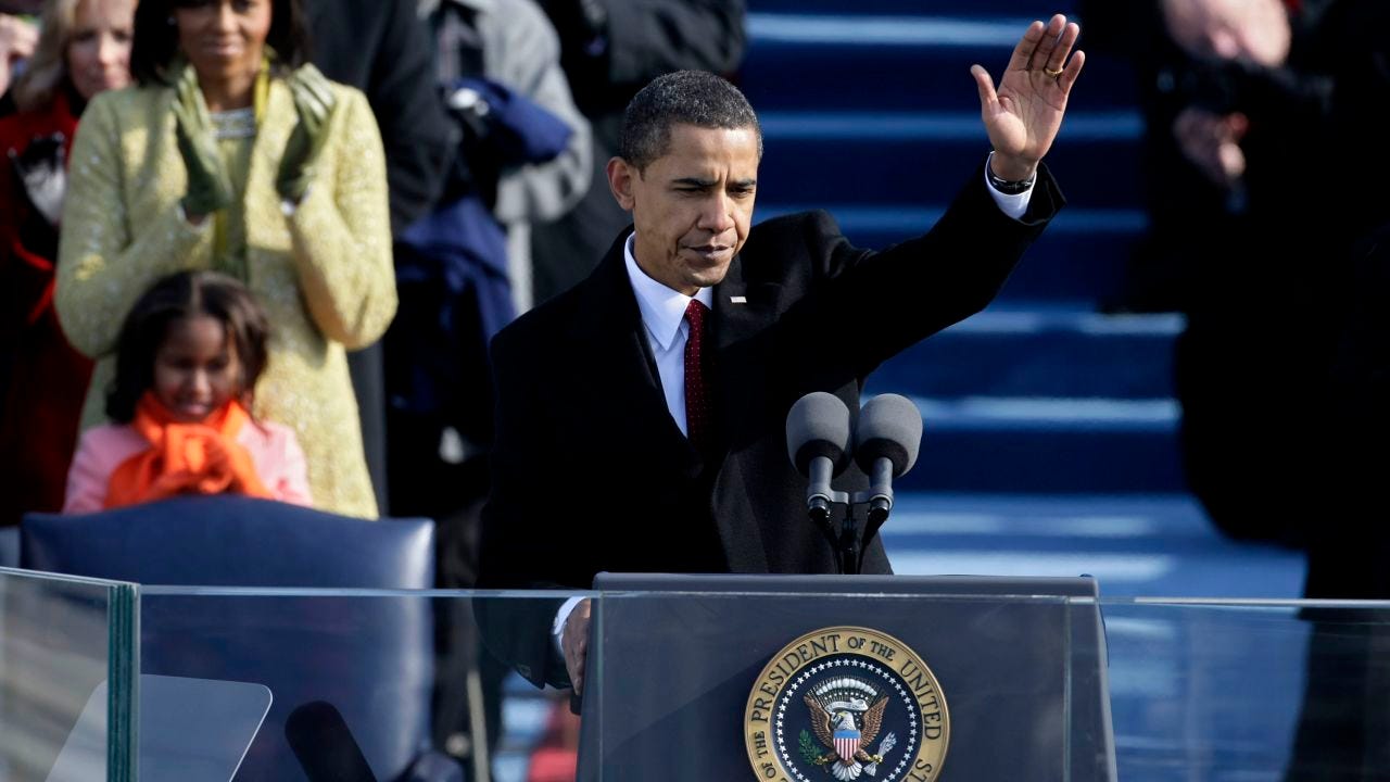 This photo shows President Barack Obama standing at the presidential podium and waving to the off-camera crowd assembled on Washington, D.C.'s National Mall on 20 January 2009 to hear his first inaugural speech. His daughter Sasha Obama and his wife, First Lady Michelle Obama, stand behind and to the image's left of the president. This photo shows President Barack Obama standing at the presidential podium and waving to the off-camera crowd assembled on Washington, D.C.'s National Mall on 20 January 2009 to hear his first inaugural speech. His daughter Sasha Obama and his wife, First Lady Michelle Obama, stand behind and to the image's left of the president.