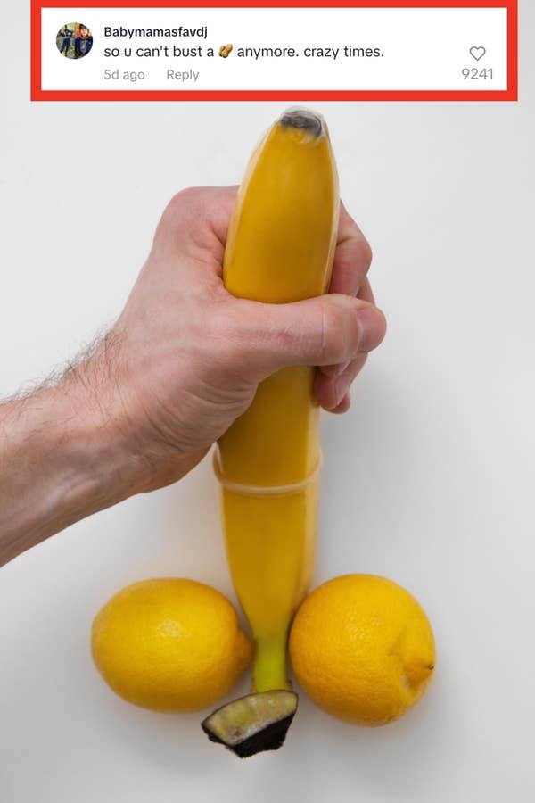 Hand holds a banana standing upright, positioned above two lemons on a white background