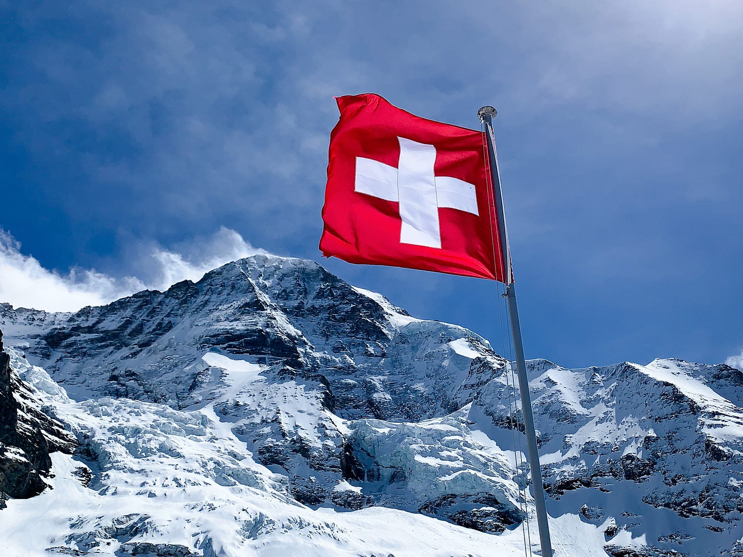 Photo of a snowy mountain peak and Swiss flag