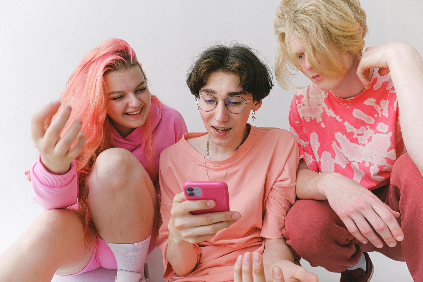 three people wearing pink looking at a smartphone