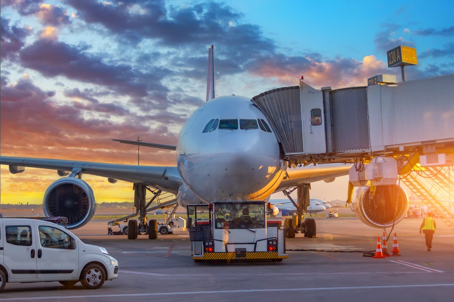 An aircraft waiting at a gate at an airport at sunset. 