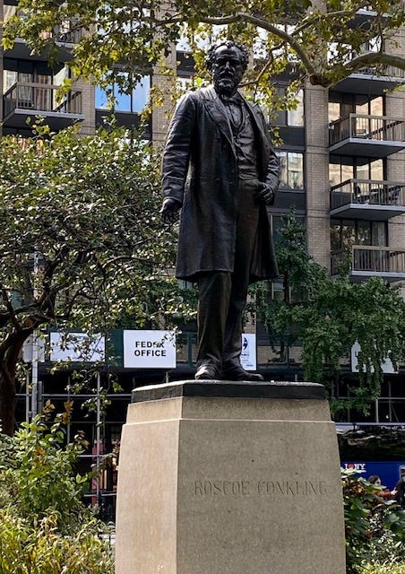 A statue of Roscoe Conkling in Madison Square Park. His left hand is by his side with his palm out and his right thumb is jauntily tucked into his pocket.