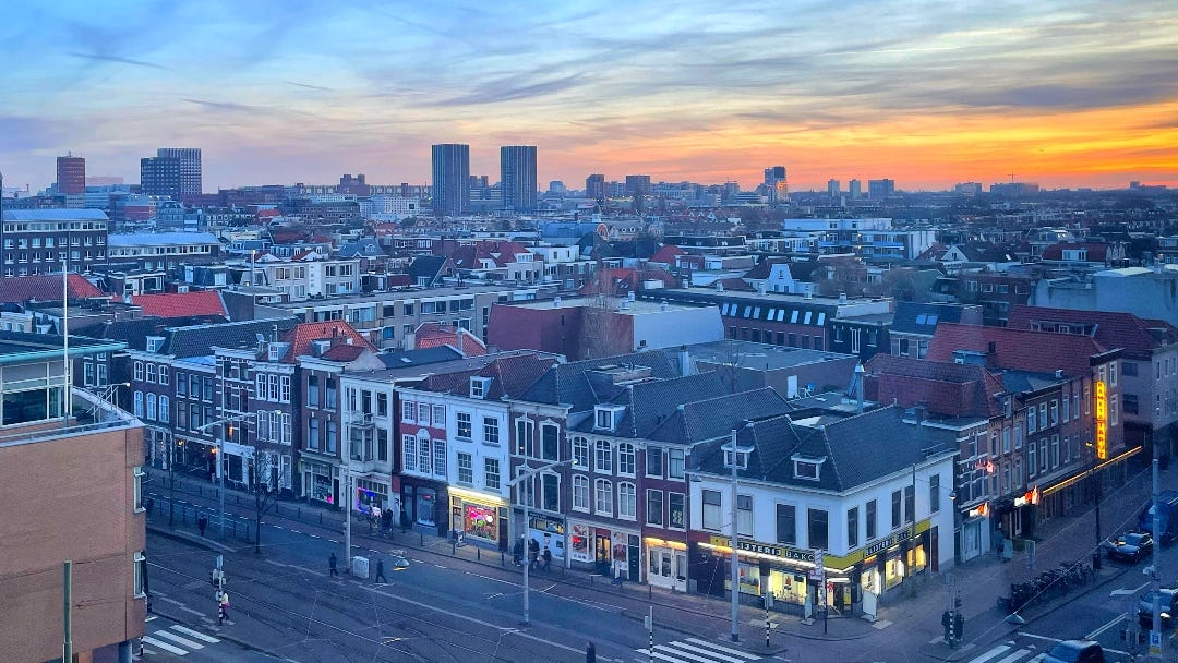 a stunning sunset, seen from the seventh floor of a hotel. on the foreground old houses of The Hague that look a bit like classic houses along the canals in cities like Amsterdam