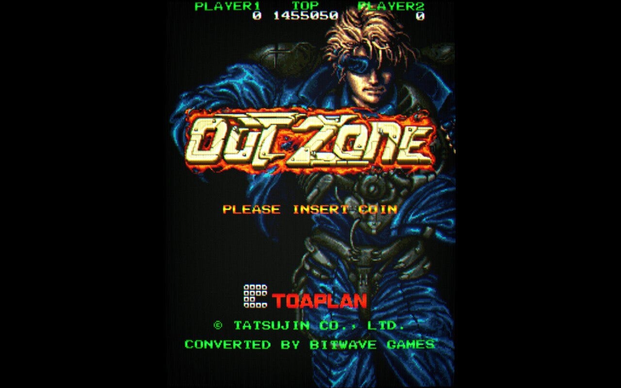 A screenshot of the title screen for the lone home conversion of Out Zone, which came out for Windows by way of Bitwave Games in 2023. It features detailed art of one of the game's two playable cyborgs, standing behind the game's text logo. As this is the Windows version, in addition to the Toaplan credit, there is also a Tatsujin one, as well as Bitwave Games for the conversion. 