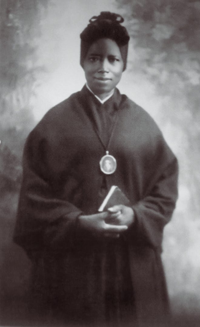 A photo of Saint Josephine Bakhita holding a book and wearing an Our Lady Miraculous Medal.
