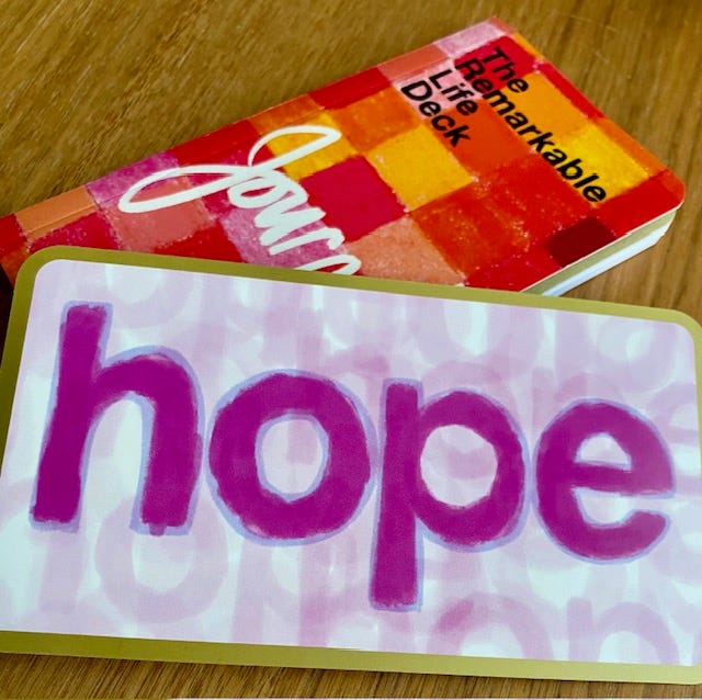 Photo of a card with the word "hope" in purple letters. A small journal is in the background.