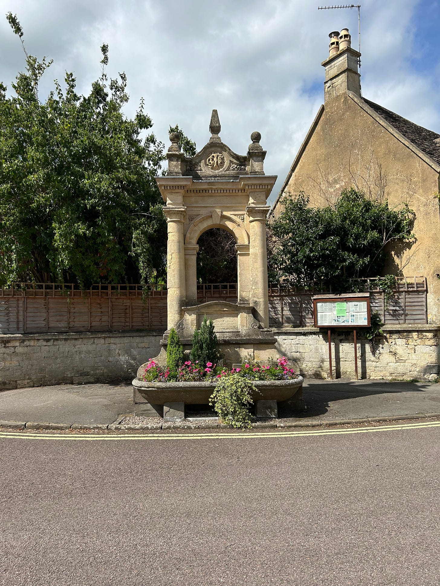 The Charles Mayo Memorial. It stands on the corner of Priory Street and High Street, Corsham. It is made of stone and has an ornate top above the two rising columns and archway. 