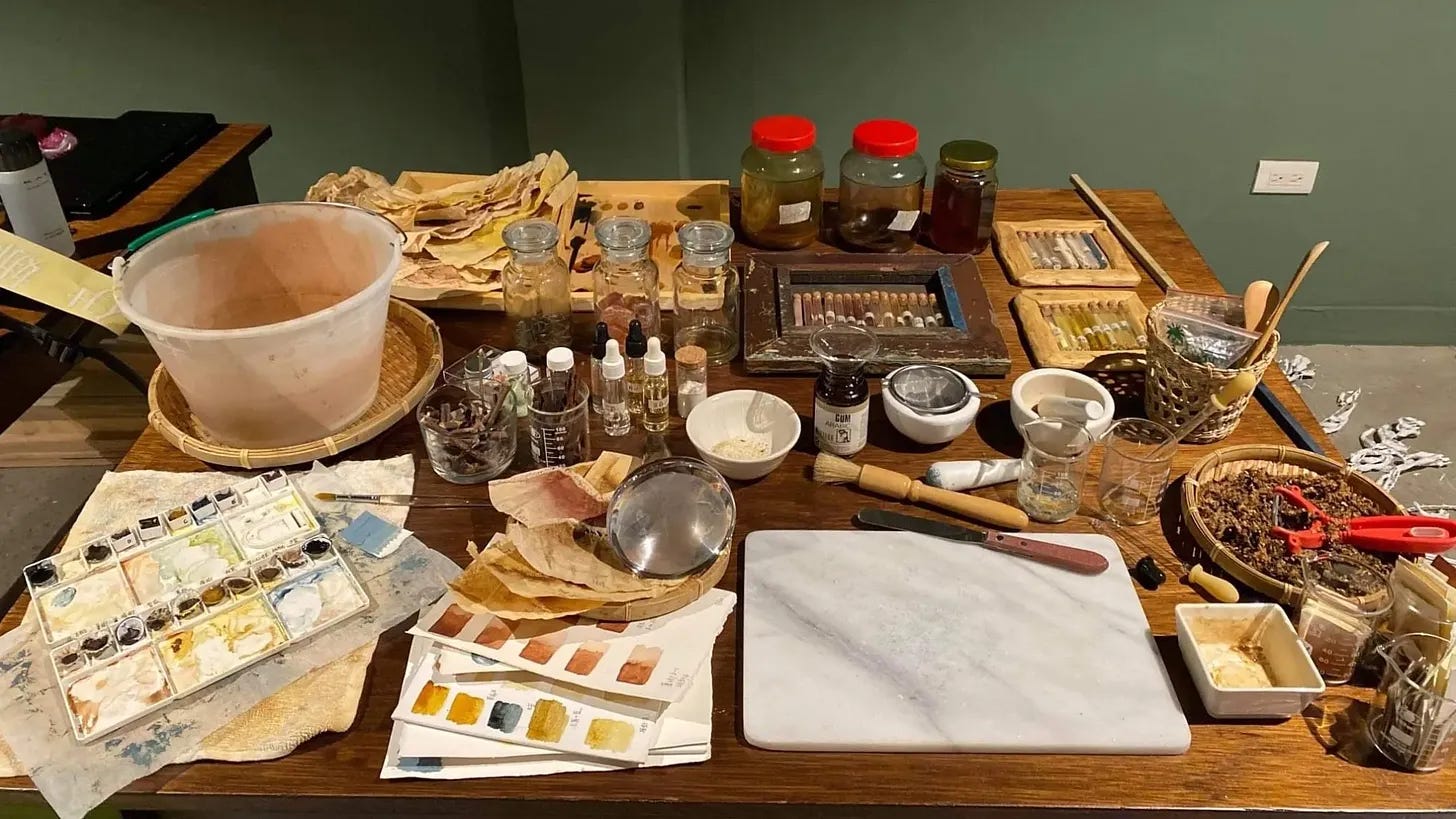 table full of natural materials and art supplies with jars, bottles and paint pots