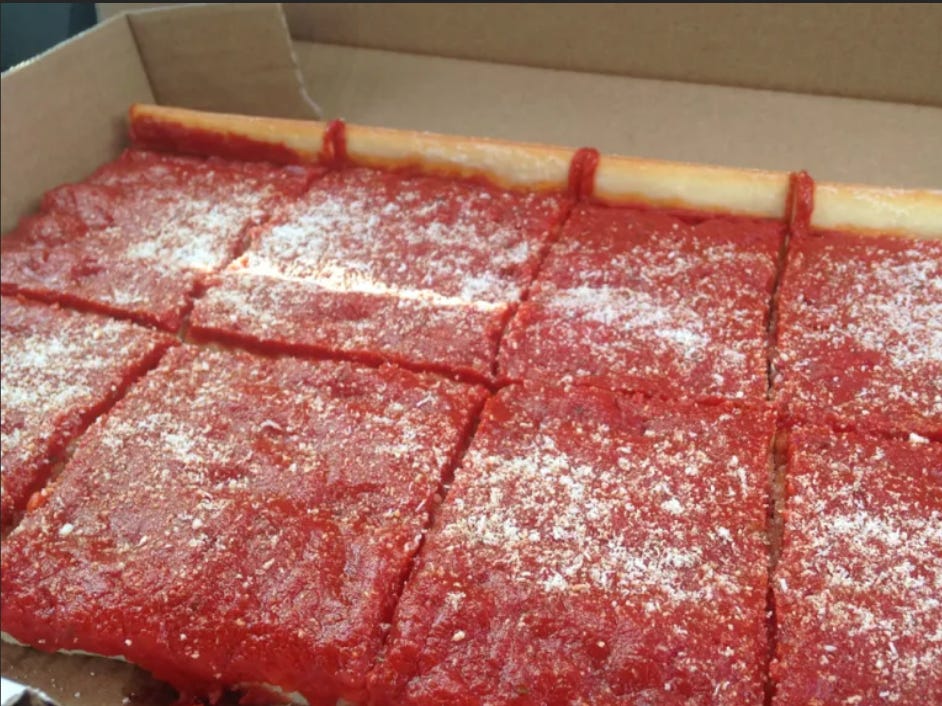 photo of a box containing a bread covered in a layer of tomato sauce