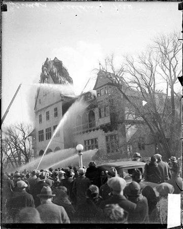 Streams of water spraying from ground level and from a fire truck ladder onto the German Building during a fire - Chicago Daily News, Inc.