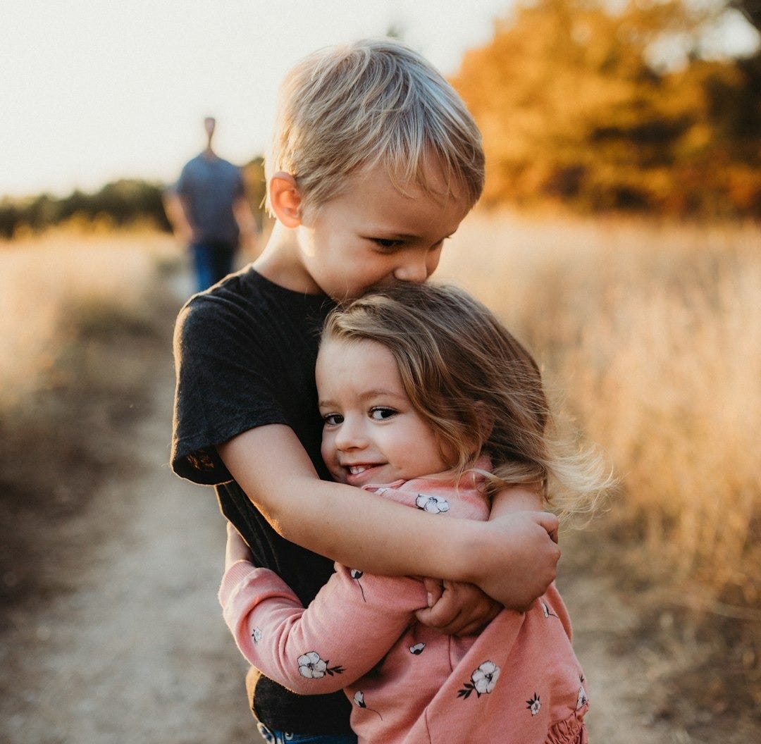 boy in black t-shirt hugging girl in red and white polka dot dress boy in black t-shirt hugging girl in red and white polka dot dress