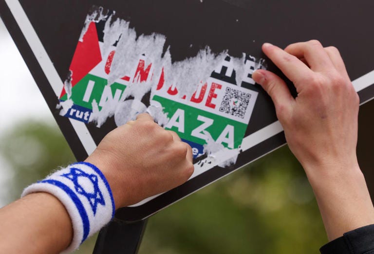 A pro-Israel activist peels a pro-Palestinian sticker off a sign on May 2 as a protest encampment was dispersed. ((Brian van der Brug / Los Angeles Times))