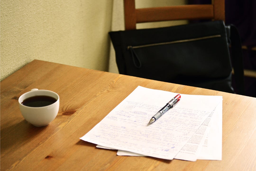 papers, red pen and a cup of coffee on a table