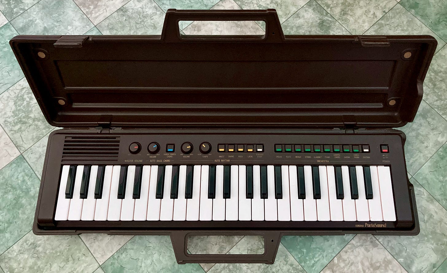 A Yamaha Portasound PS-3 music keyboard in its open case
