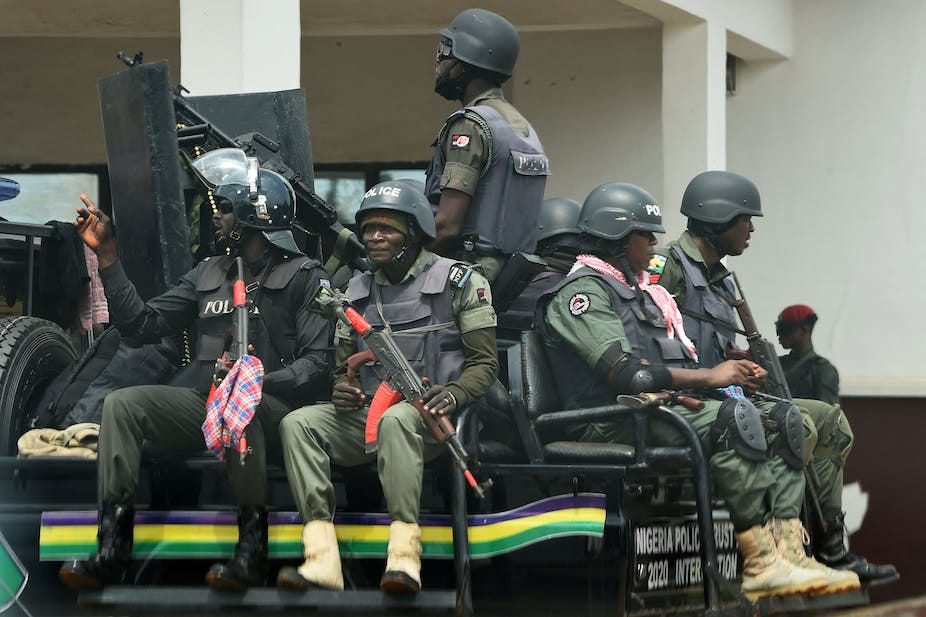 Men in riot police gears, sit on a gun-mounted vehicle