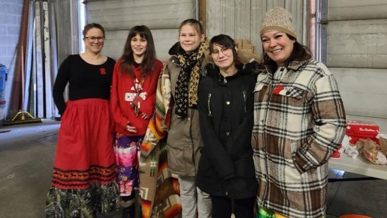 A group of five women are pictured smiling to the camera.