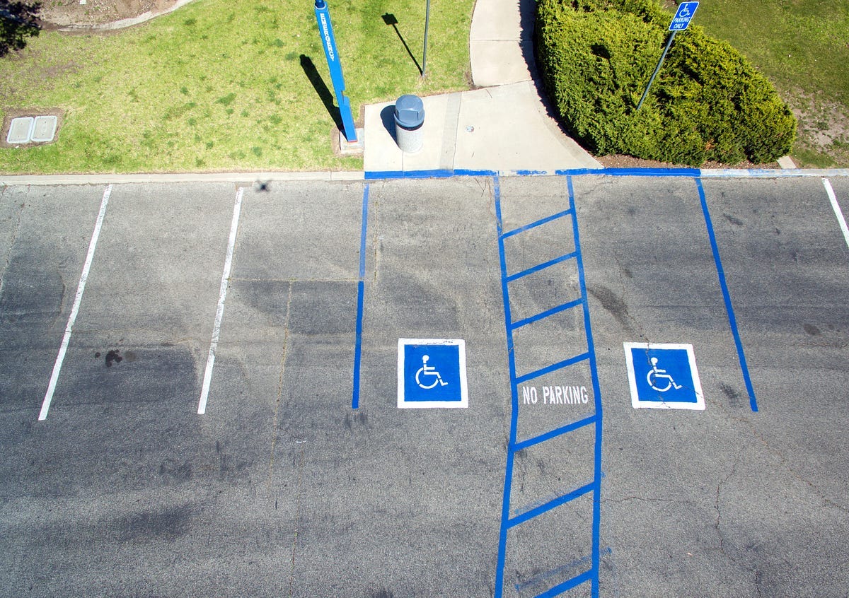 Bird’s eye view of parking lot with two accessible parking spaces leading to an accessible concrete path