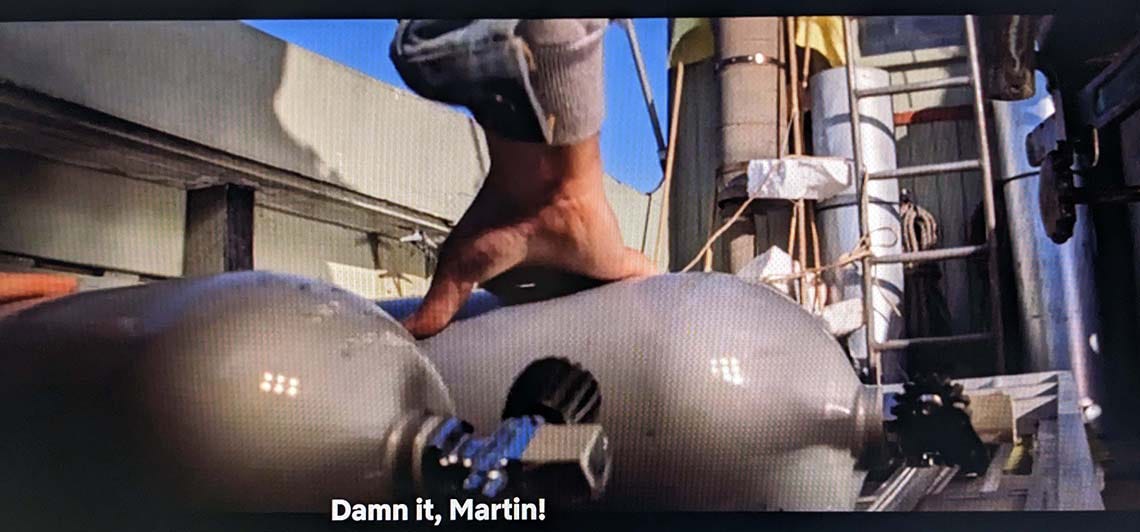 A still from Jaws: A cannister of compressed air rolling on a boat's deck. Cooper (off-screen) is saying 'Damn it, Martin!'