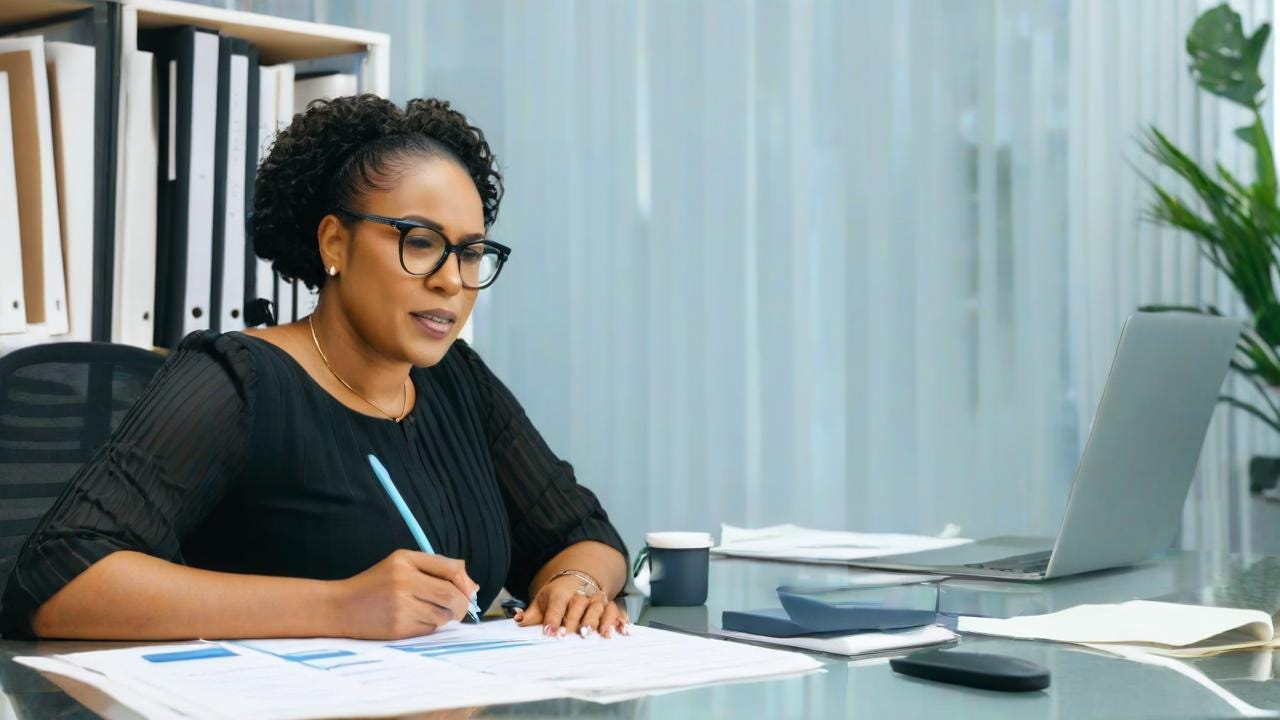 Black Woman wearing glasses life Coaching sitting sitting in office with water on the table with a laptop and writing on the papers with client