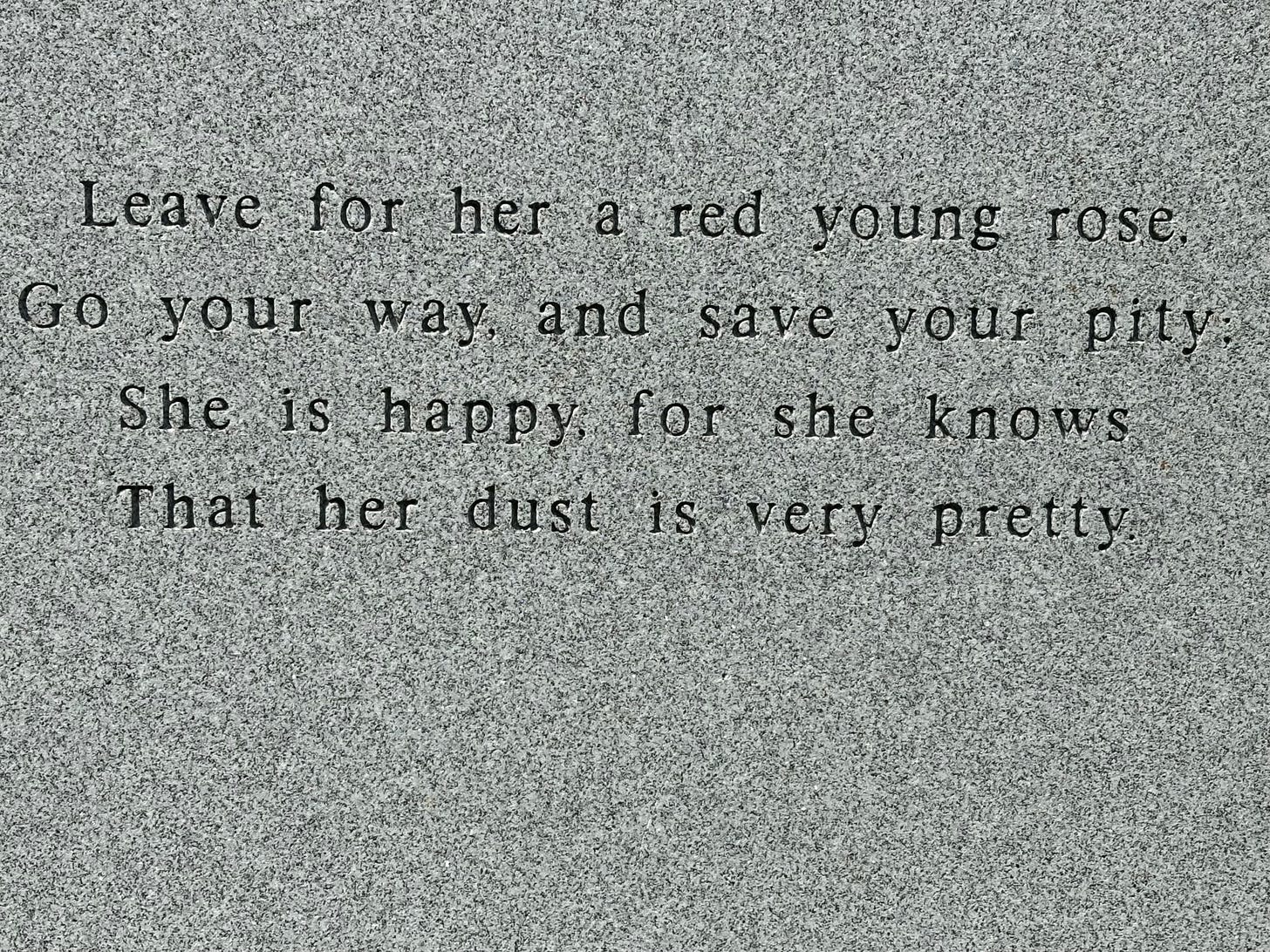 A close-up of Parker's epitaph. It reads: "Leave for her a red young rose, Go your way, and save your pity; She is happy, for she knows That her dust is very pretty."