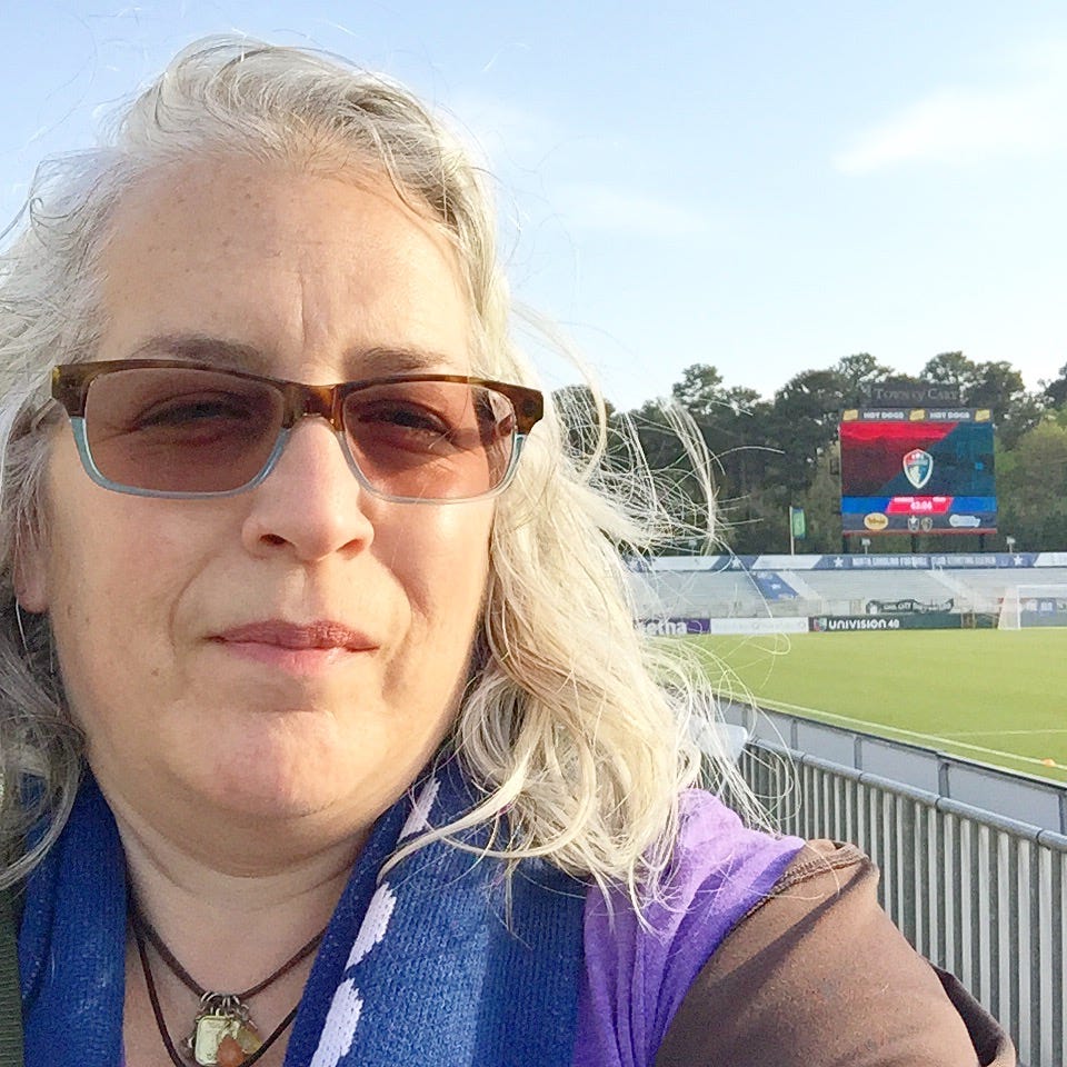 selfie at WakeMed Soccer Park with stadium seats and scoreboard with NC Courage logo in background