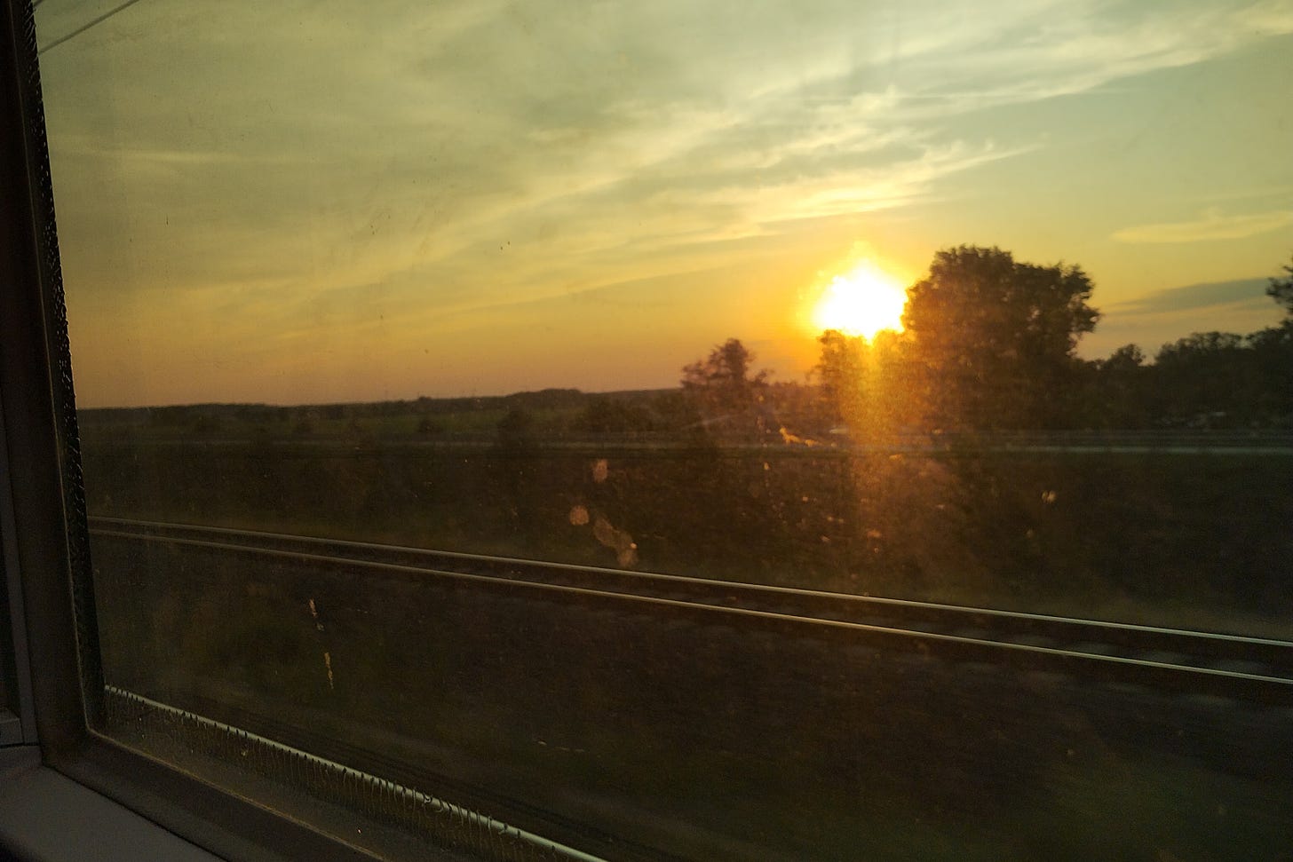 View of a sunset over a field from a train window