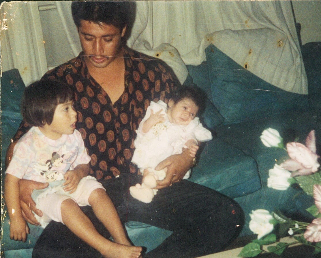A father sits on a green couch holding two young children A father sits on a green couch holding two young children