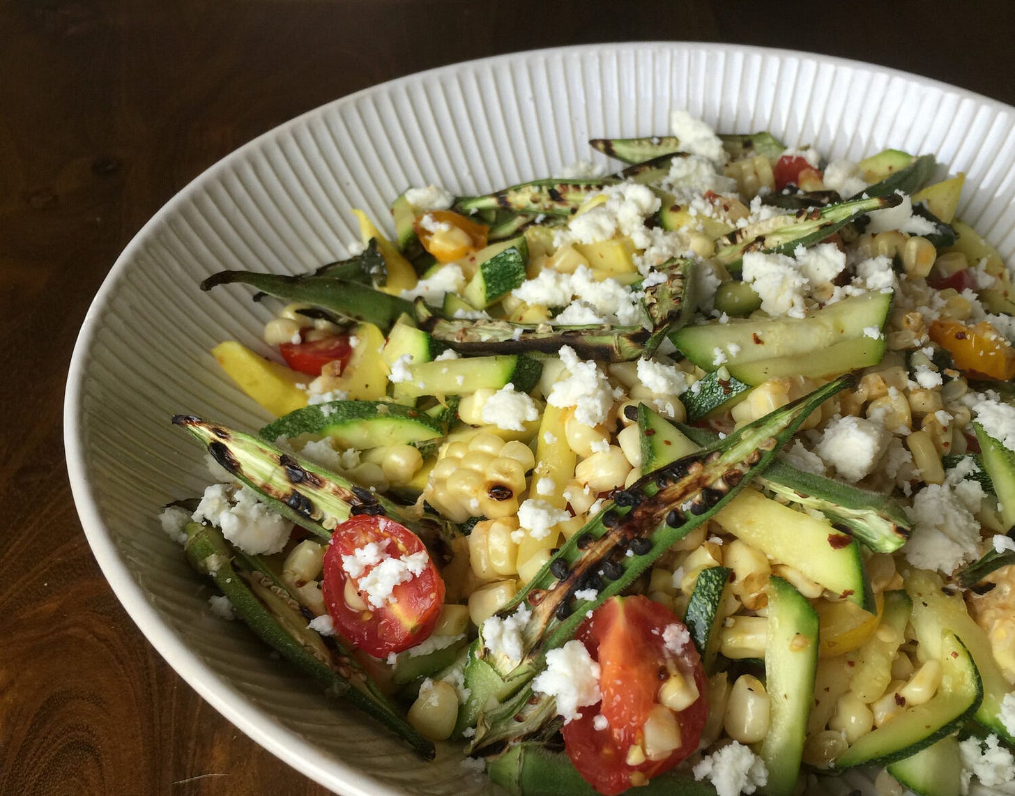 Warm summer salad with grilled corn, tomatoes, okra, zucchini, herbs and queso freso