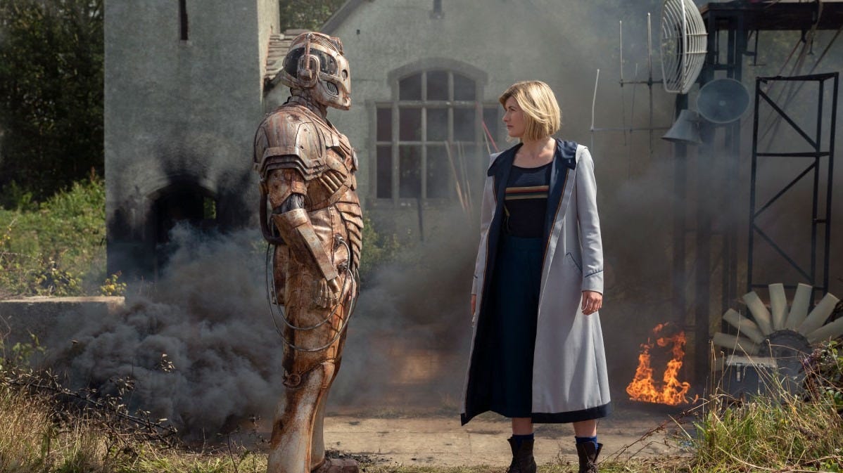 This image from "Ascension of the Cybermen" (Doctor Who Series 12's ninth episode) shows Ashad (played by Patrick O'Kane, left) and the Thirteenth Doctor (played by Jodie Whittaker, right) standing on the grounds of a battle-blasted village that may be humanity's final refuge after the Cyber Wars have devastated the galaxy. This image from "Ascension of the Cybermen" (Doctor Who Series 12's ninth episode) shows Ashad (played by Patrick O'Kane, left) and the Thirteenth Doctor (played by Jodie Whittaker, right) standing on the grounds of a battle-blasted village that may be humanity's final refuge after the Cyber Wars have devastated the galaxy.