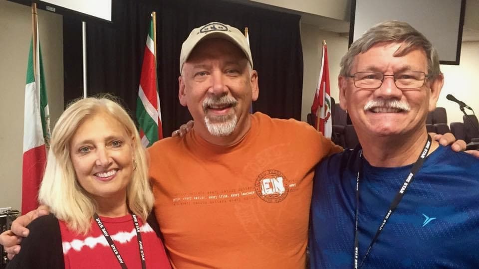 Image of a woman and two men smiling at the camera.