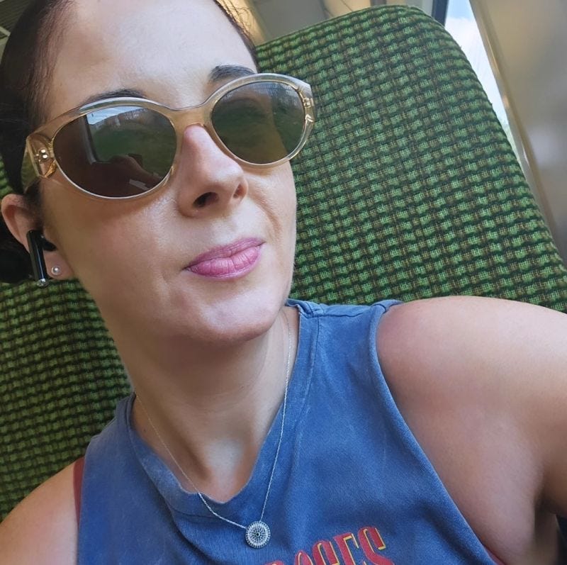 Woman on a train with sunglasses on smiling