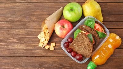 a group of snack foods including apples, grapes, cheese and a sandwich