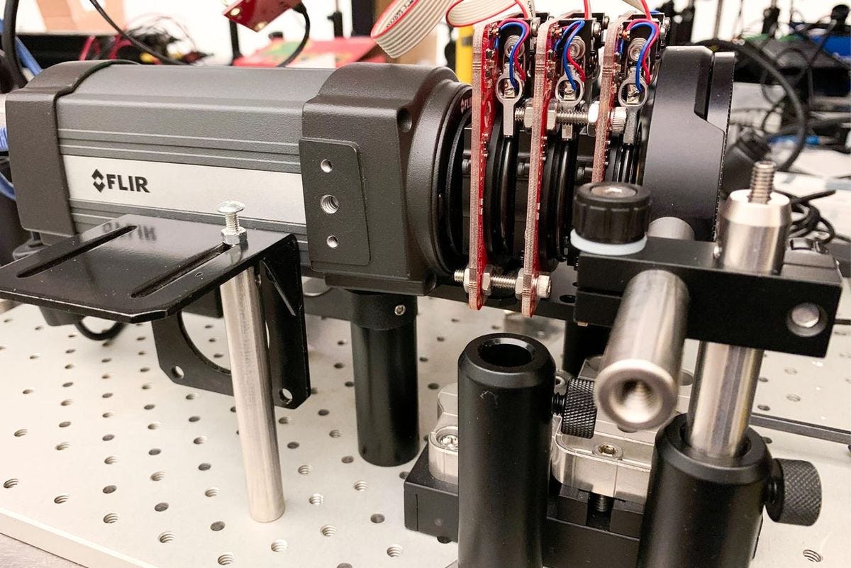 A horizontal device labelled FLIR consists of a closed box on the left and on the right, circular disks interspersed with red circuitboards and wires.