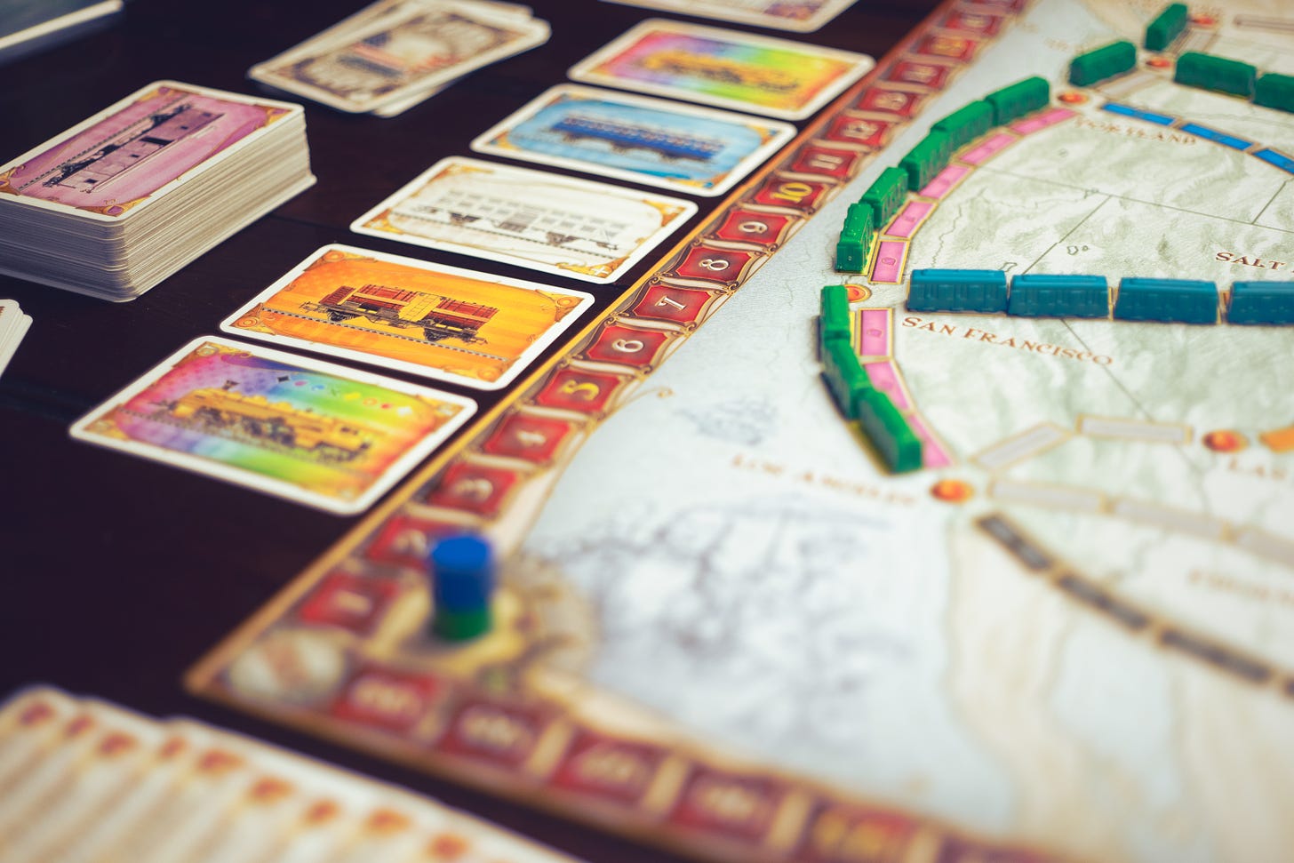 The game Ticket to Ride on a table. There are train pieces on a board, and there are train cards to the left of the board awaiting selection.