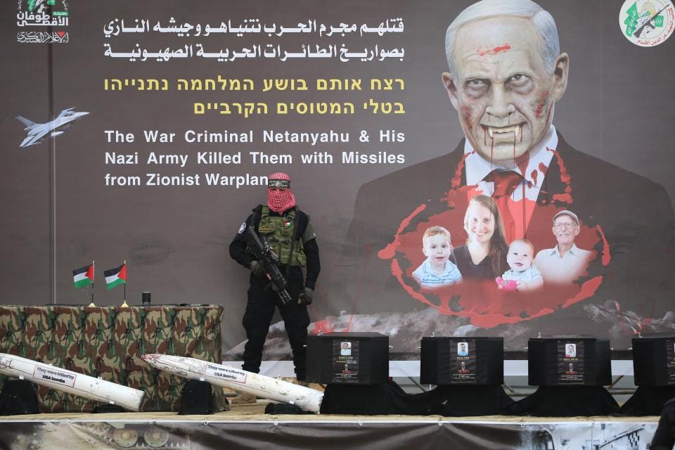 A Hamas fighter stands in front of a banner bearing an altered portrait of Israel's Prime Minister and the Bibas family, on stage ahead of the handing over the bodies of four Israeli hostages in Khan Yunis in the southern Gaza. Photo: AFP A Hamas fighter stands in front of a banner bearing an altered portrait of Israel's Prime Minister and the Bibas family, on stage ahead of the handing over the bodies of four Israeli hostages in Khan Yunis in the southern Gaza. Photo: AFP