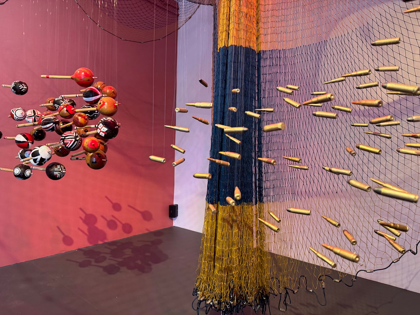 An art installation by Ziel Karapoto in which bullets suspended in a net are on the right-hand side, while maracas dangle on the left-hand-side An art installation by Ziel Karapoto in which bullets suspended in a net are on the right-hand side, while maracas dangle on the left-hand-side