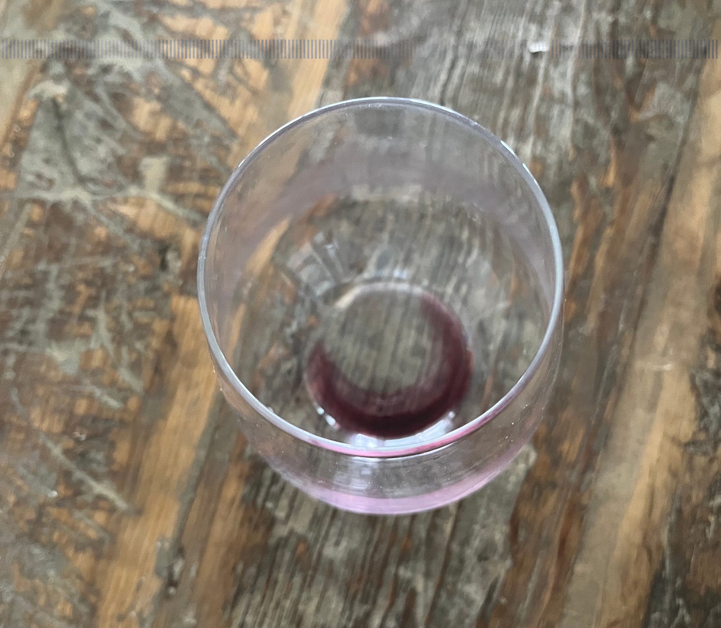 Empty glass of red wine in a stemless glass on a wood table