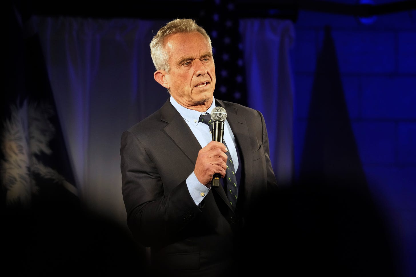 Robert F. Kennedy Jr. holds a mic and speaks during a campaign event.