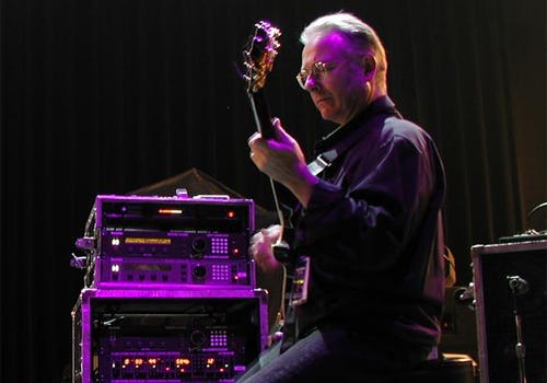 Profile image of Robert Fripp playing guitar onstage. Photo: “robert fripp” by Sean Coon from Greensboro, USA
