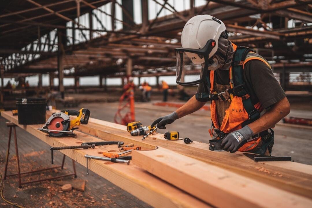 man in orange and black vest wearing white helmet holding yellow and black power tool man in orange and black vest wearing white helmet holding yellow and black power tool