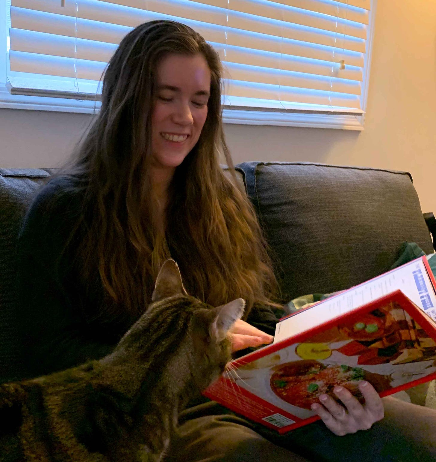 Kayla Stark and her cat Squidge looking through a cookbook