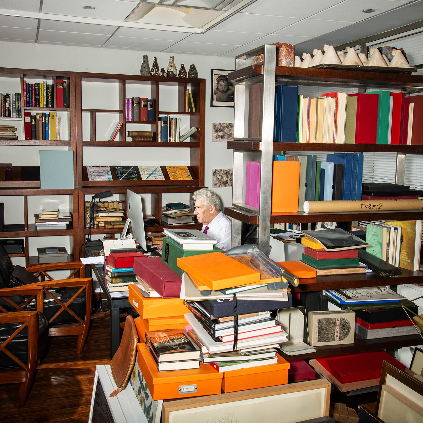 Glenn Horowitz sits at a desk surrounded by boxes and books.