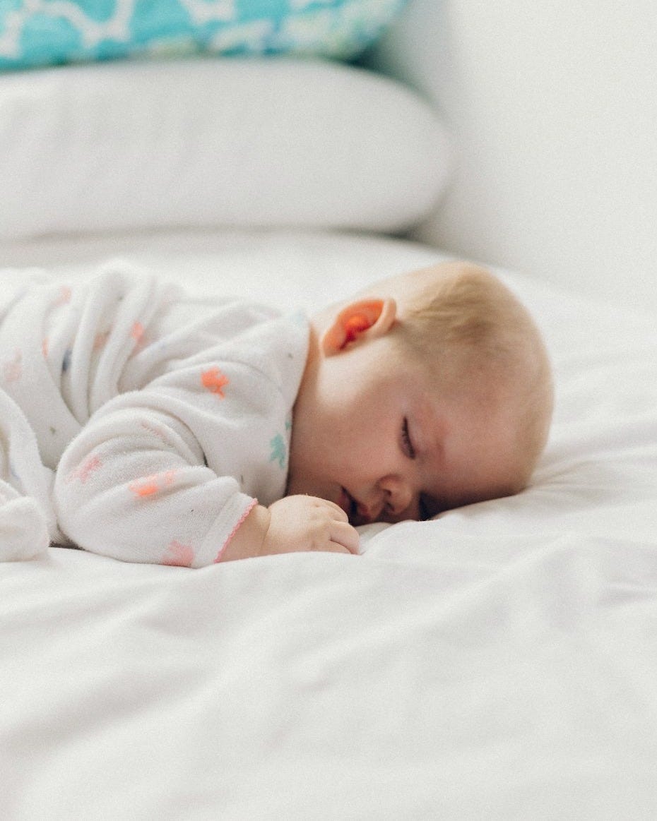 photo of baby laying on bed