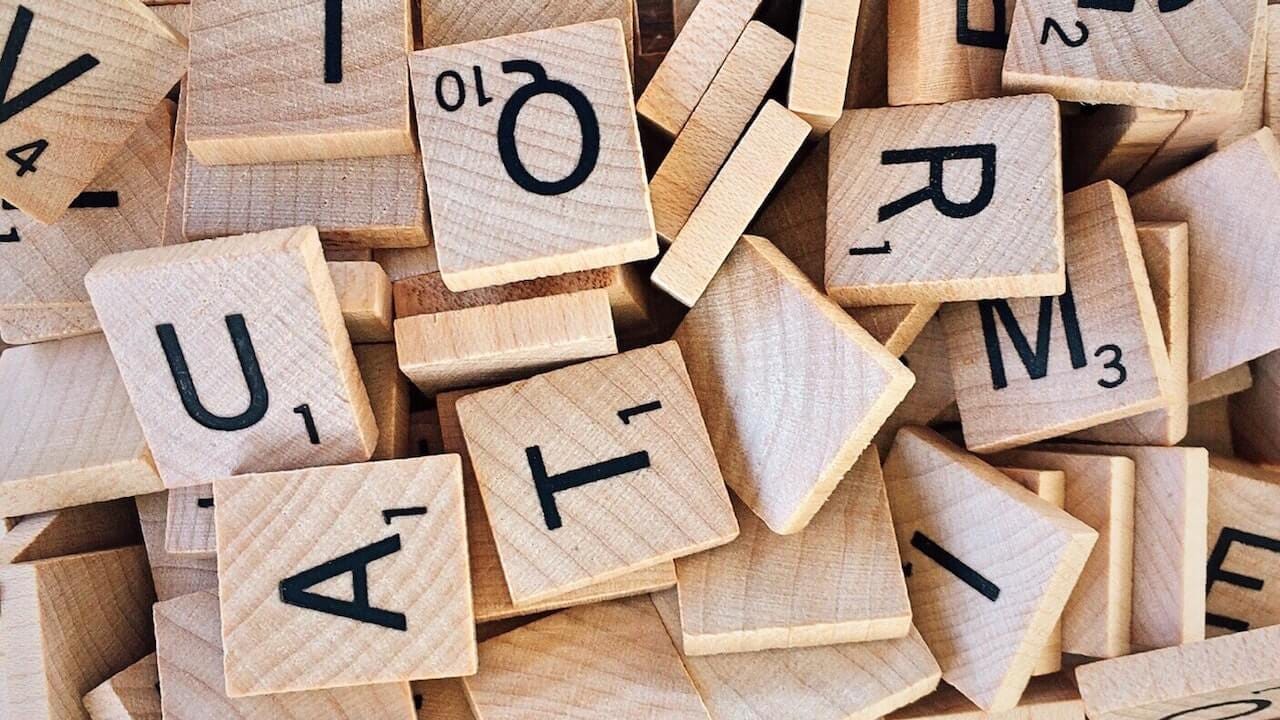 Small wooden cutout squares with letters and numbers on them used in the boardgame Scrabble.