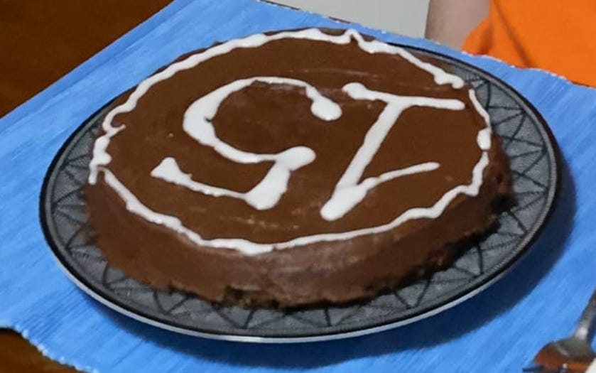 a single-layer chocolate-frosted cake with the number 15 written on it in white icing. The cake is pictured upside down.