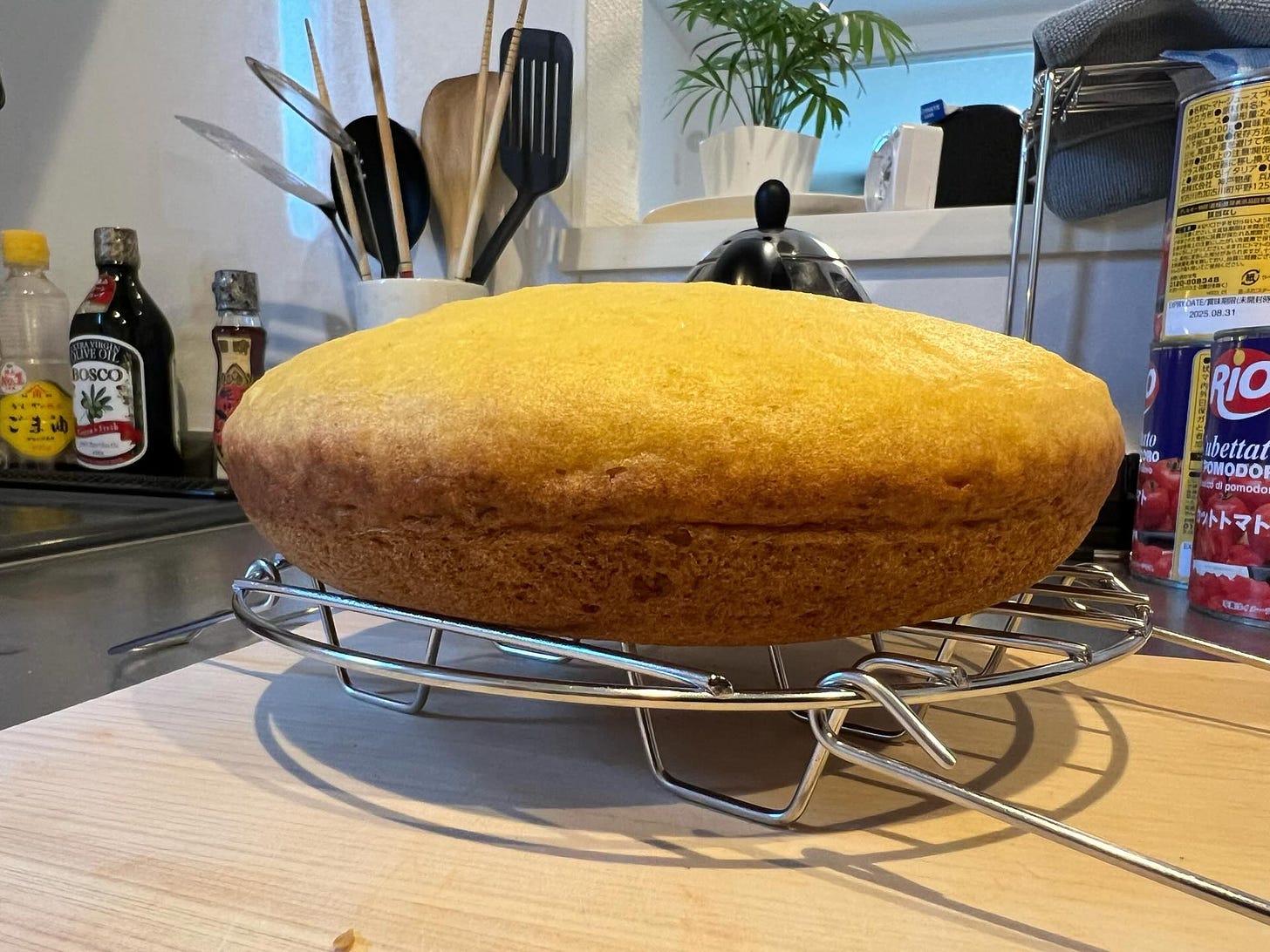 A cornbread made in a rice cooker cooling on a rack in a kitchen.