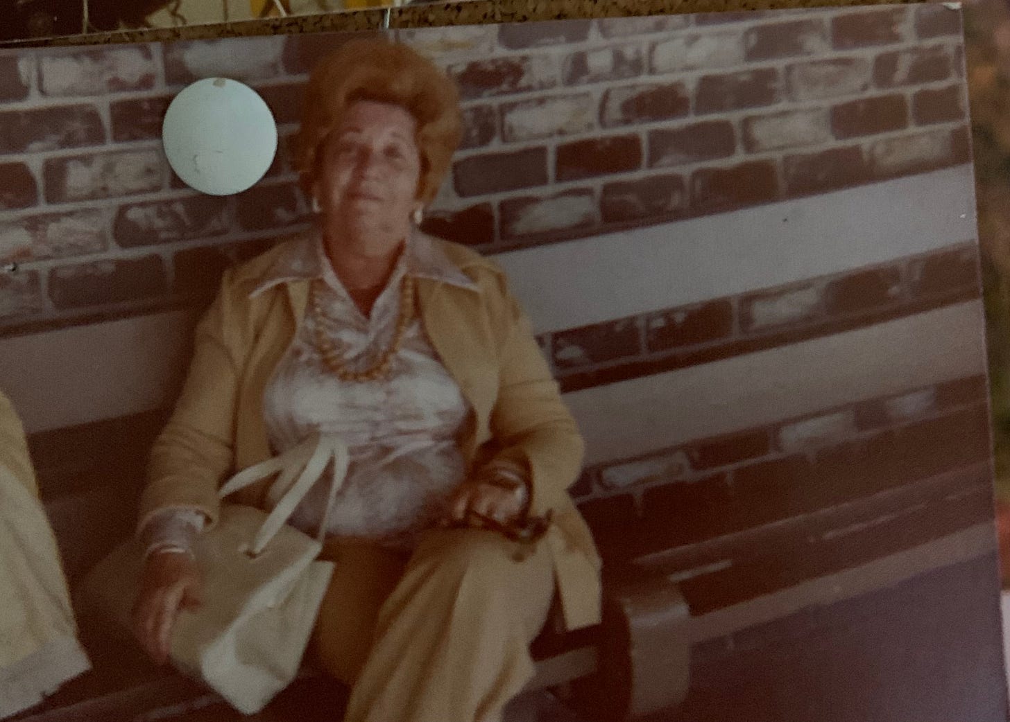 A badass Jewish woman with big hair sits on a bench