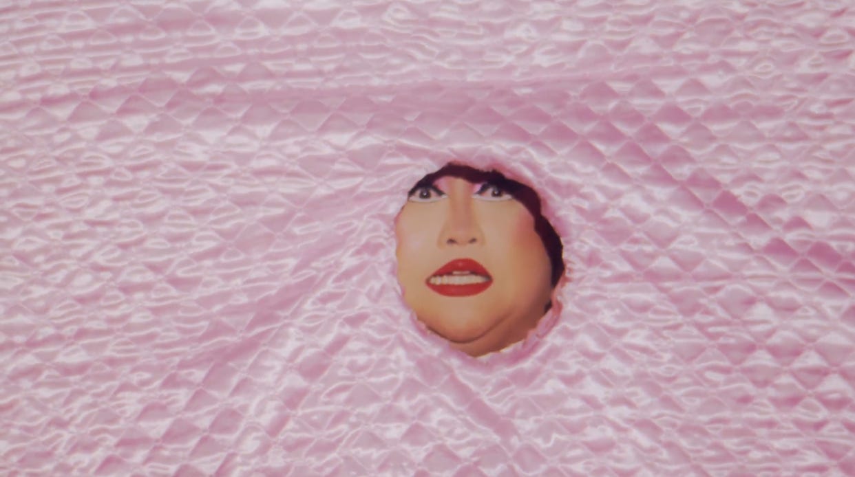 Joella in her quilted runway look with just her face exposed through a hole in the front