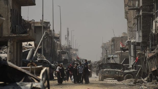 Iraqi people carrying what possessions they can hold escape from Islamic State.